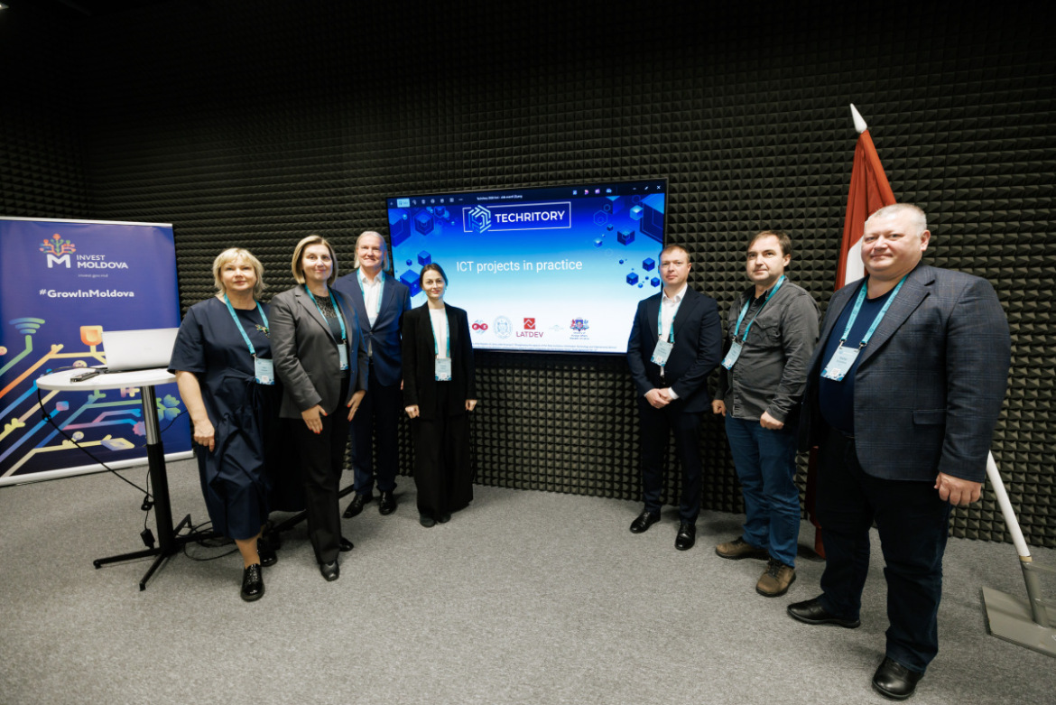 Techritory foruma sesijas “ICT projects in practice” dalībnieku kopfoto pie prezentācijas ekrāna un “Invest Moldova” stenda.
